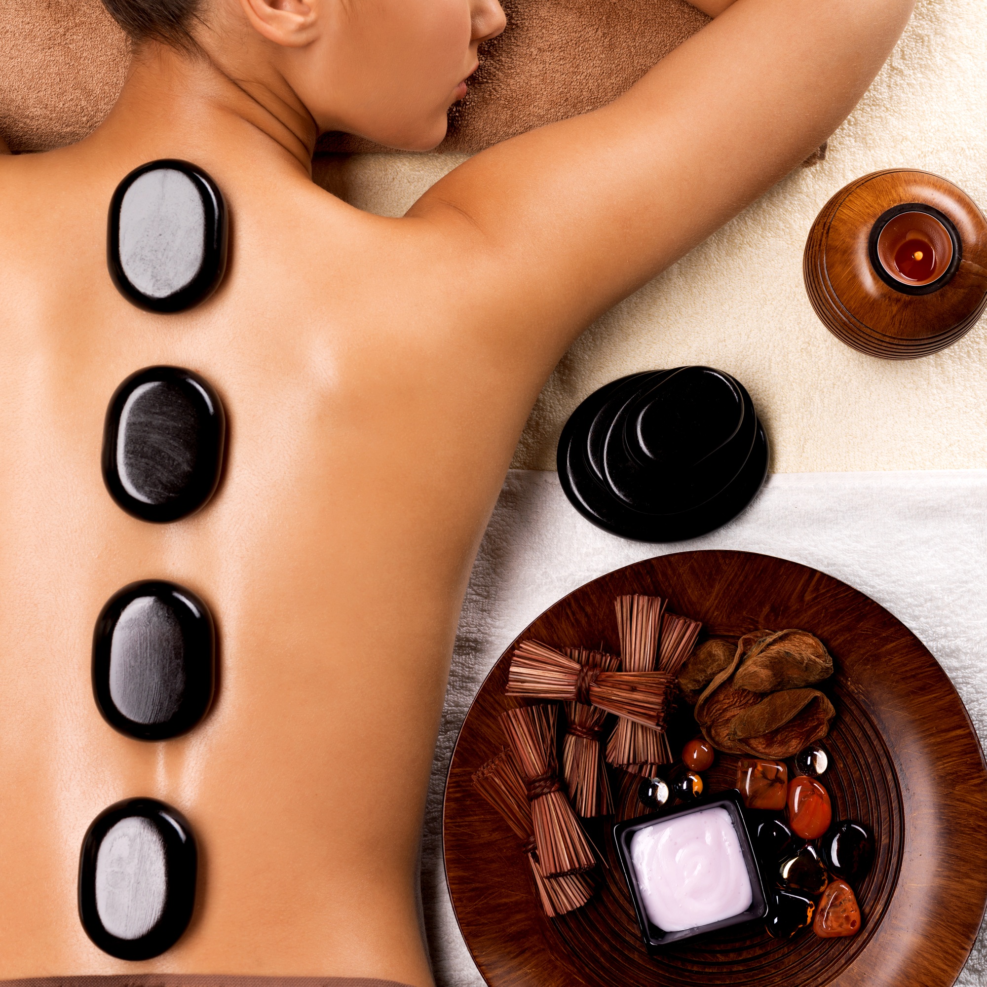 Young woman getting hot stone massage in spa salon.